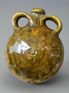 Glazed earthenware saddle jug/hip flask decorated with slip made from natural raw materials and a green glossy glaze.