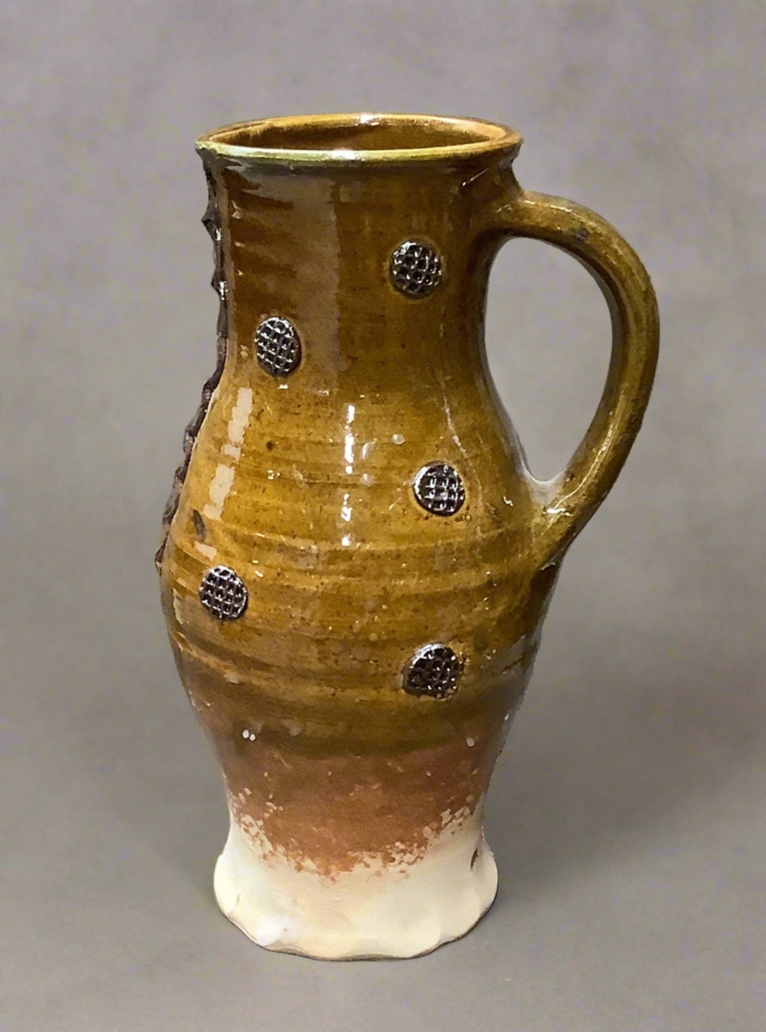 Yellow earthenware jug decorated with cross hatched circular motifs, slip made from natural raw materials and a glossy glaze.