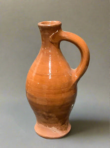 Tall earthenware jug with fluted lip, gloss glazing and handle.