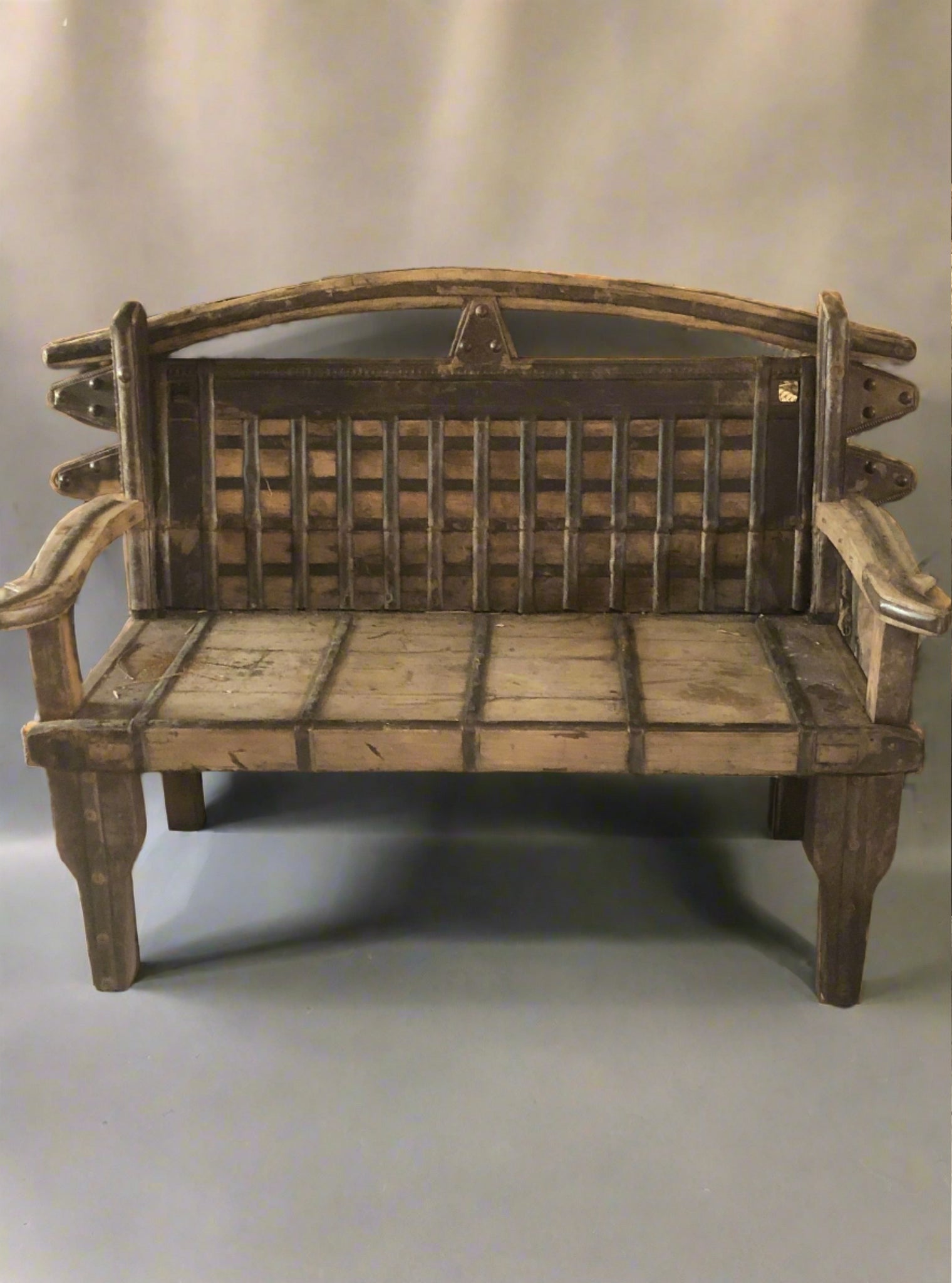 Medieval style wooden bench with unusual metal slatted panel to seat back, metal band trims and studding to legs.