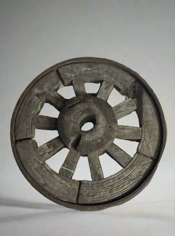 Decorative rustic antique cart wheel with metal casing and carved detailing.