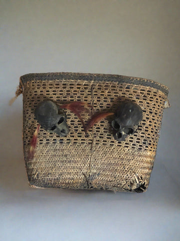 Peculiar woven bamboo basket with two decorative skulls. Creepy voodoo aesthetic.