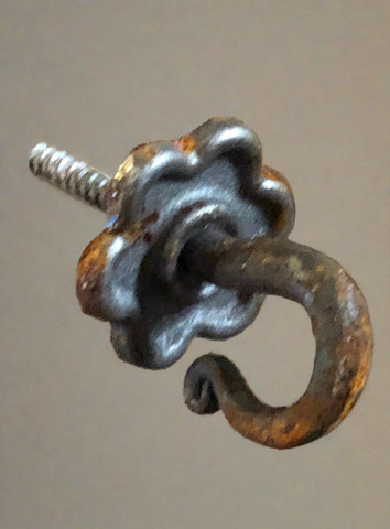 Ornate rat tail ended wrought iron hook on screw with floral shaped backplate.