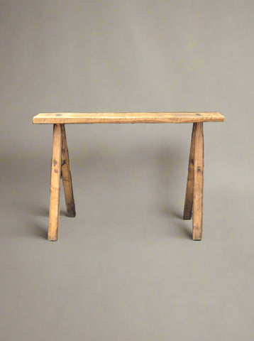 Small rustic wooden milking bench with peg construction detailing.