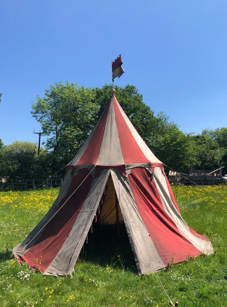 Medieval-style jousting tournament tent in red and white with scalloped trim and pennant flag.