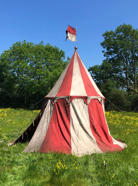 Medieval-style jousting tournament tent in red and white with scalloped trim and pennant flag.