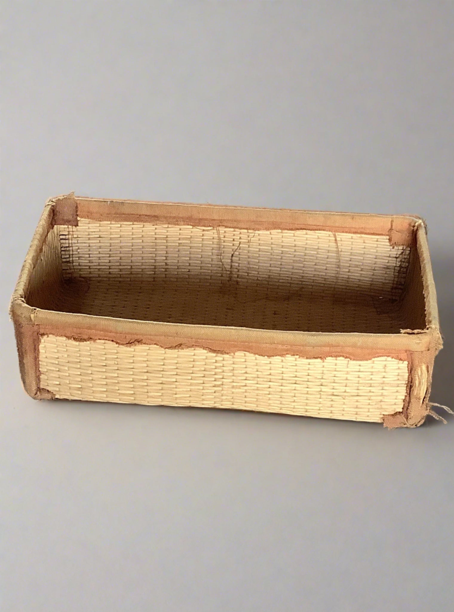 Rectangular straw tray with fabric edging, in an aged condition.